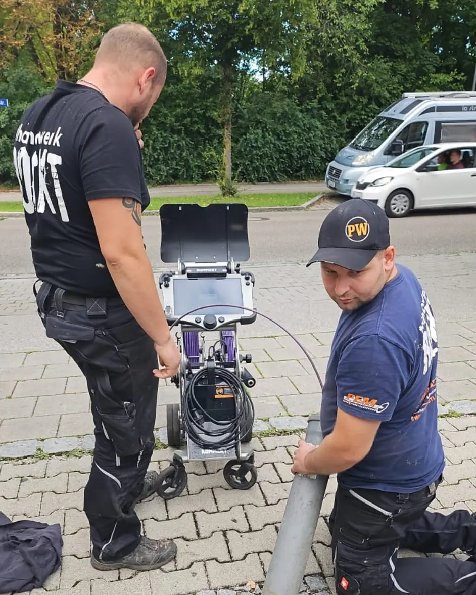 Zwei Techniker der PW Rohrreinigungs GmbH richten die Kanalkamera am offenen Schacht ein
