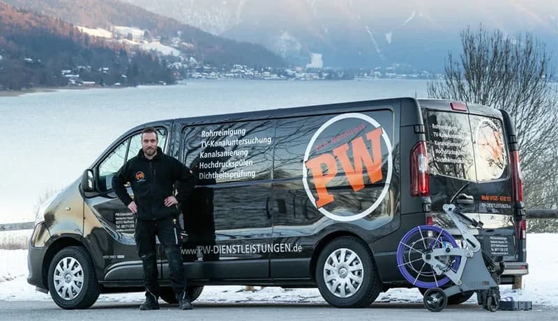 Mitarbeiter der PW Rohrreinigungs GmbH neben dem Einsatzfahrzeug vor Bergkulisse